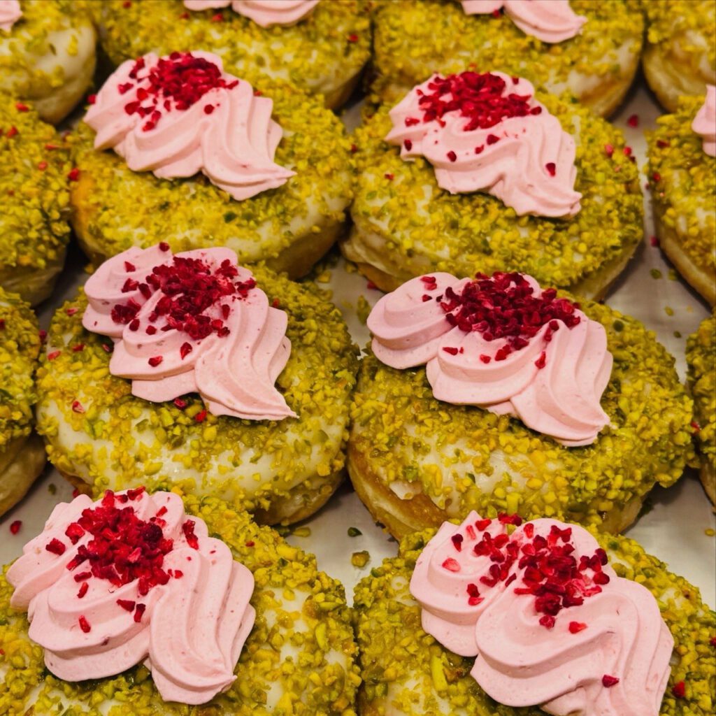 Pistachio-crusted doughnuts topped with raspberry cream and freeze-dried raspberries