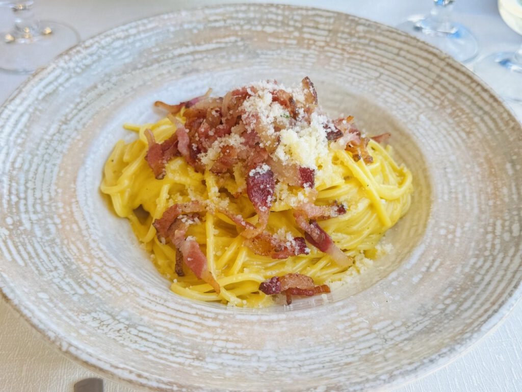 Plate of spaghetti carbonara with crispy pancetta and grated parmesan