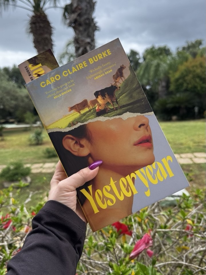 Holding a copy of the book Yesteryear by Caro Claire Burke outdoors