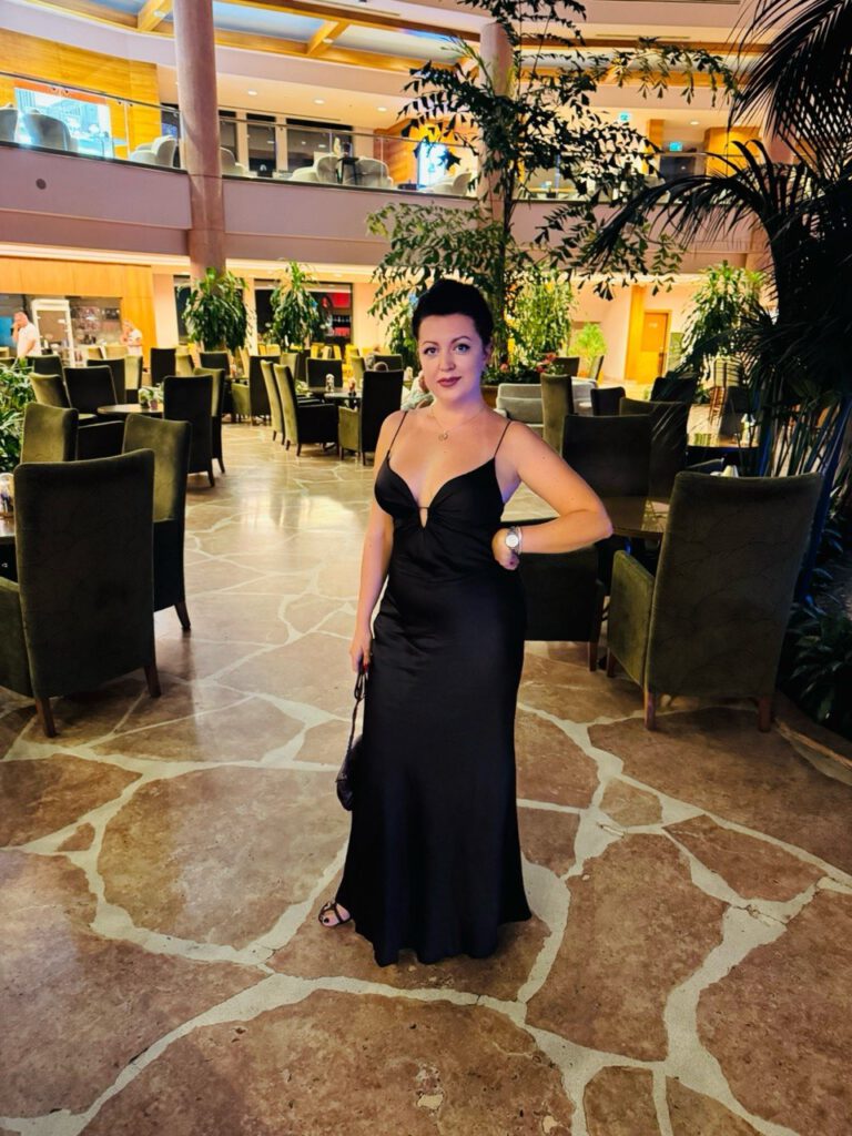 Woman in a black evening gown in a hotel lobby, dressed up for dinner
