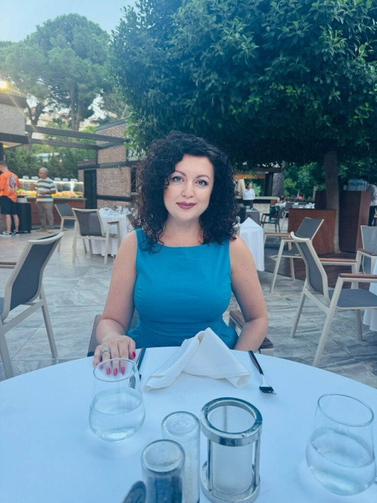 Woman in a blue dress seated at an outdoor dinner table
