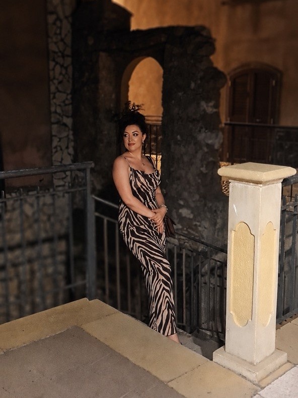 Woman in a zebra-print dress leaning against a railing at night