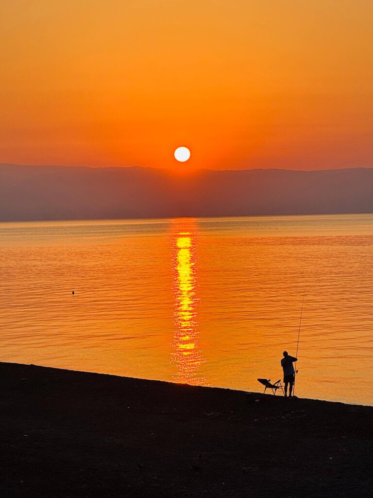 Sunrise over the sea with a fisherman silhouetted on the shore
